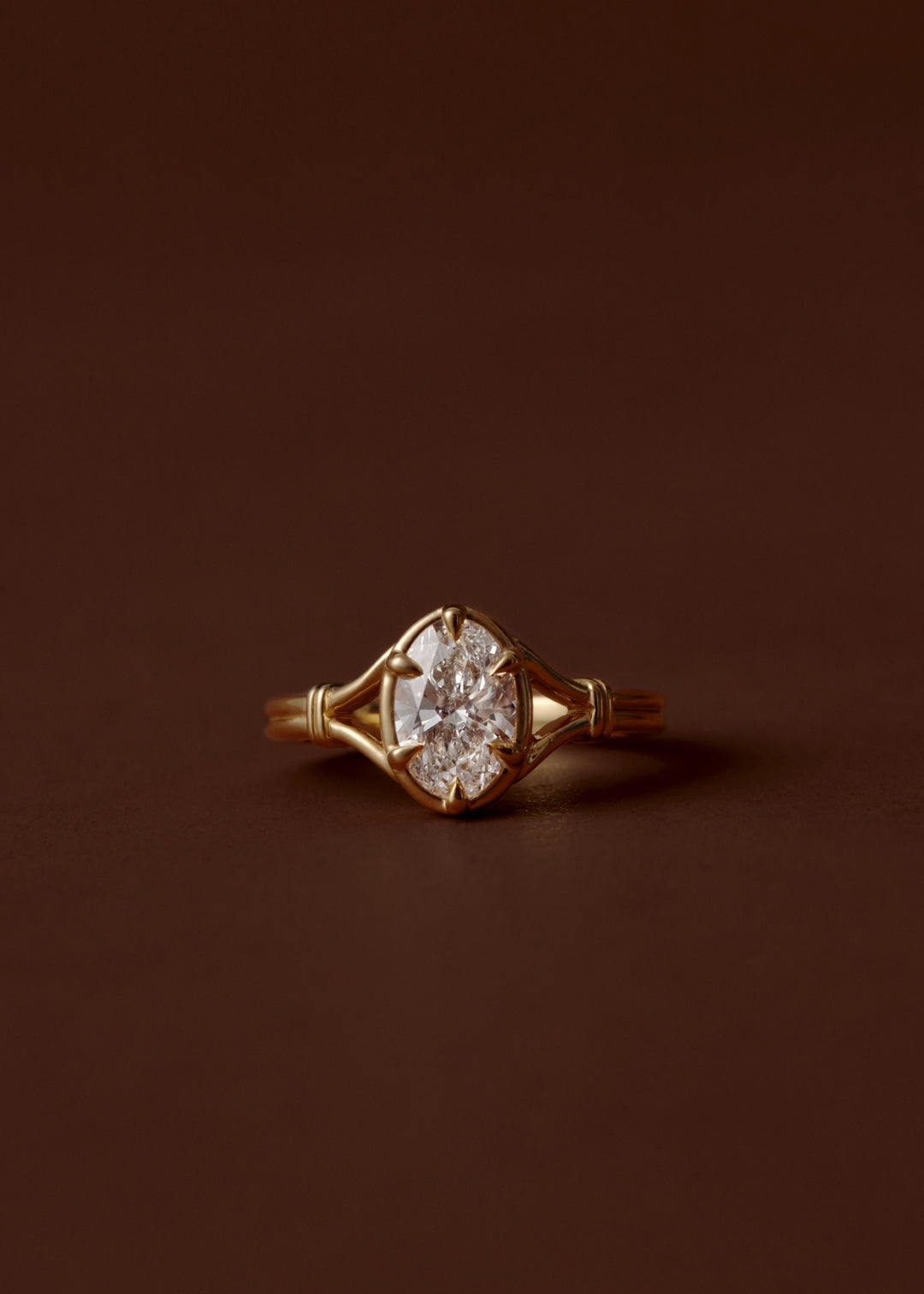 Oval diamond split shank engagement ring with six talon claws and collet setting