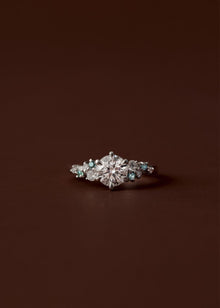 Asymmetrical sapphire and diamond cluster engagement ring with round centre diamond