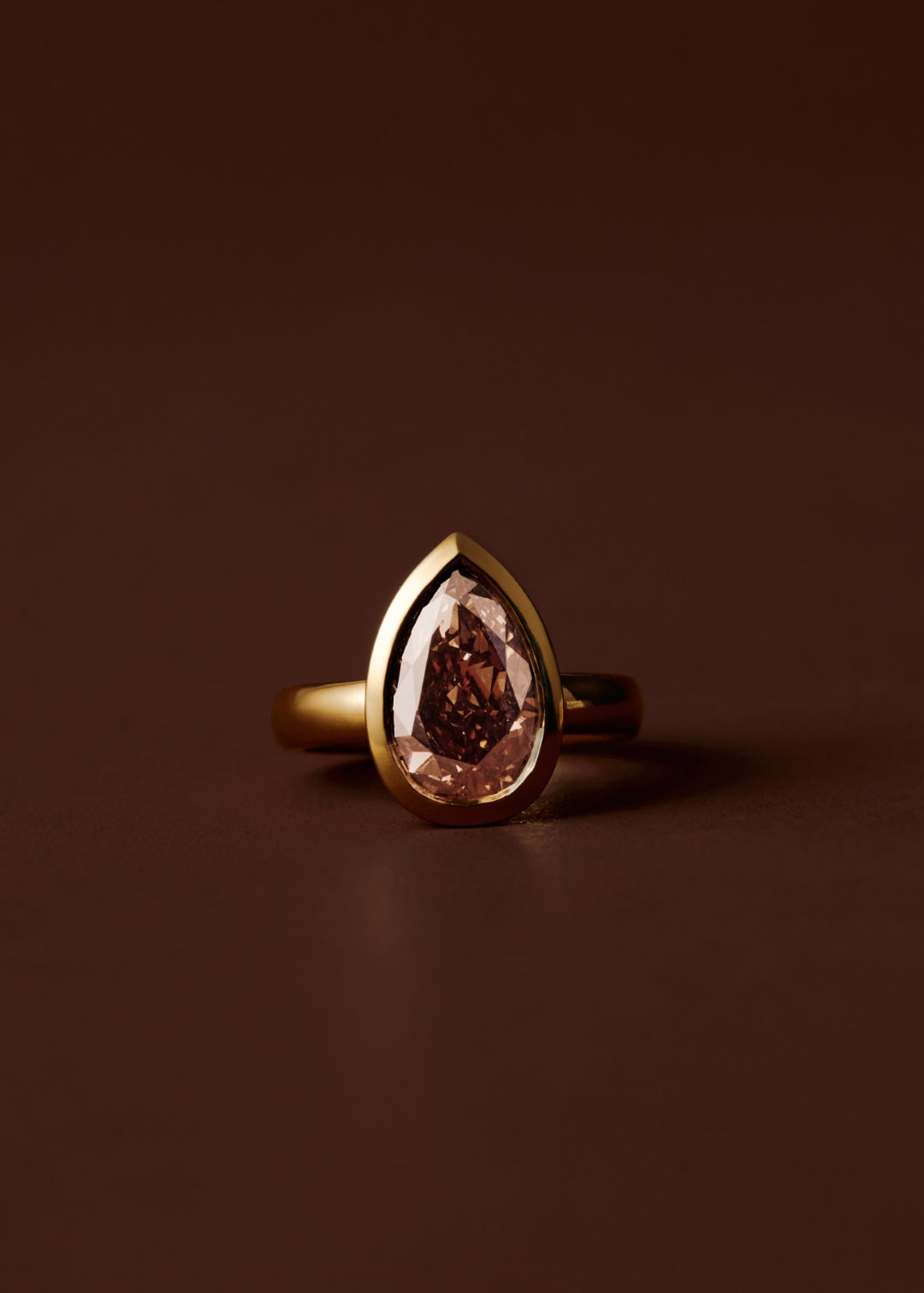 Champagne pear diamond engagement ring with bezel setting and wide gold band