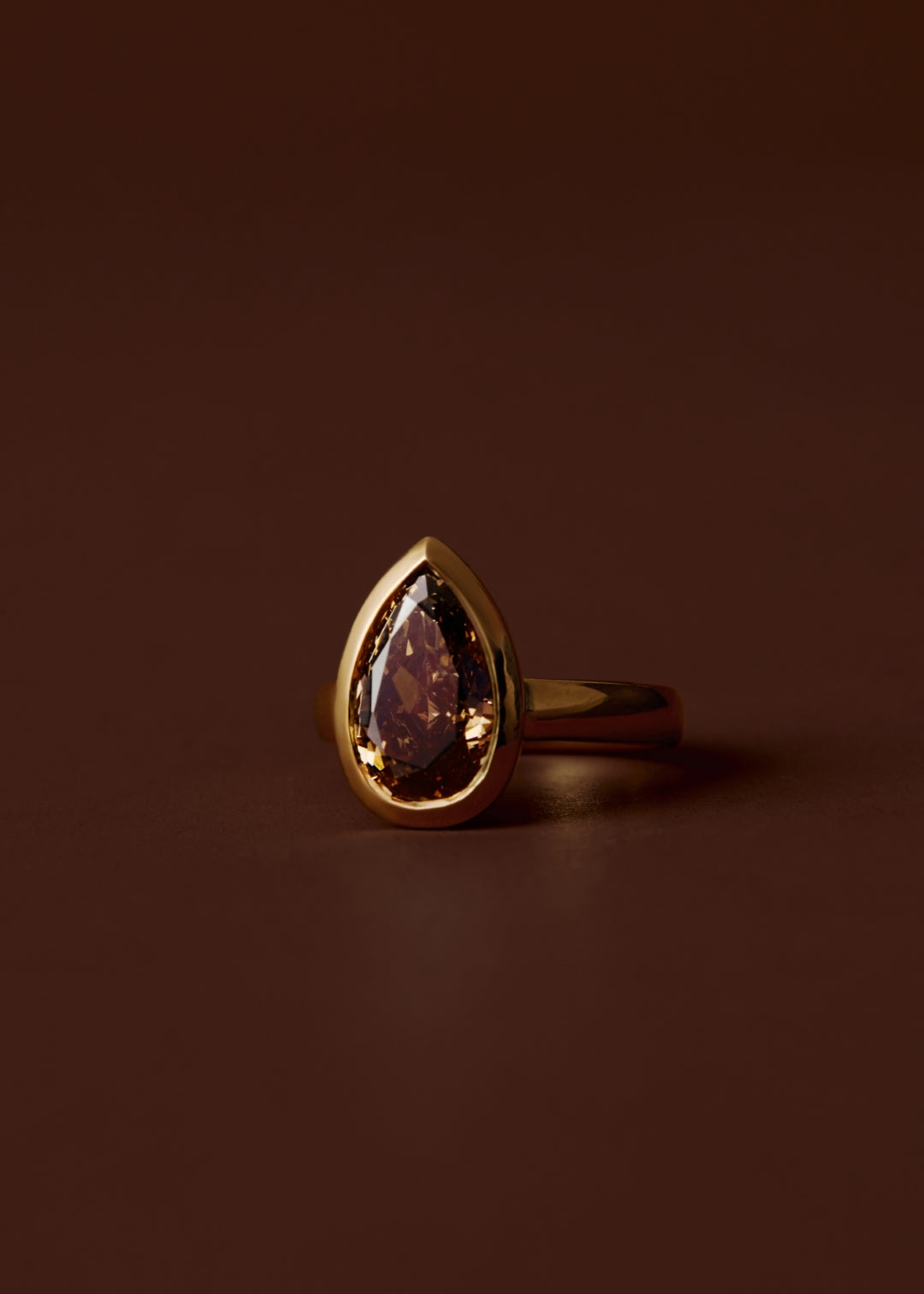 Champagne pear diamond engagement ring with bezel setting and wide gold band